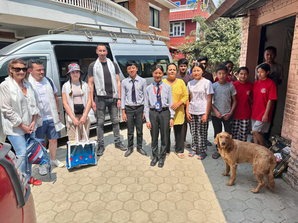 Groupe de visiteurs européens, enfants et éducateurs devant le foyer de l'Association Sagarmatha au Népal, 2025